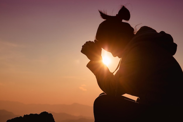 Femme silhouette sur fond de coucher de soleil. Femme levant les mains en signe d'adoration.