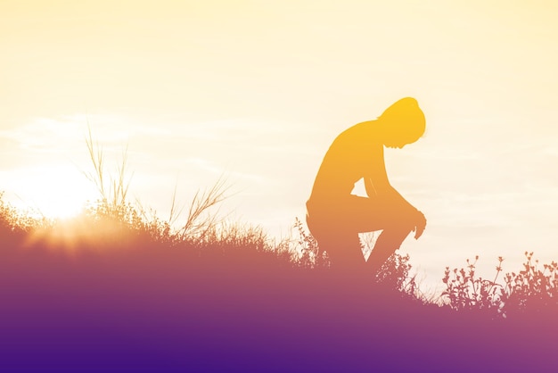 Photo femme de silhouette à genoux avec ses mains