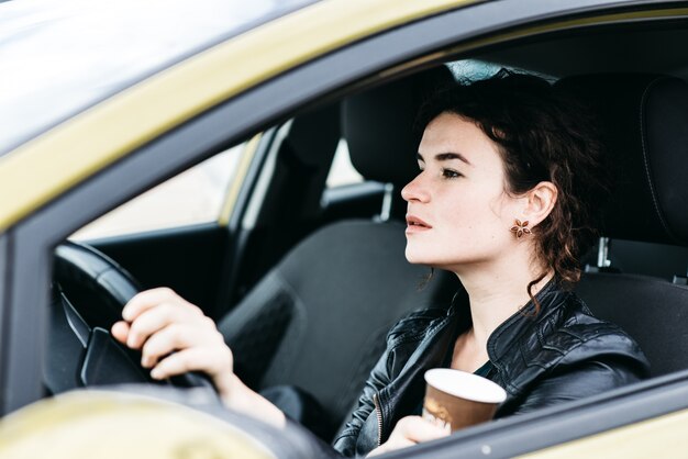 Femme en sirotant un café en conduisant une voiture.