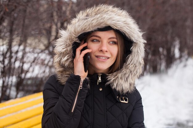 Femme avec smartphone, appelant. L'hiver.