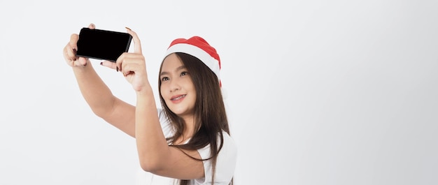 Femme et smartphone. Femme asiatique avec un smartphone à la main qui pose comme un selfie ou un appel vidéo pour une célébration en ligne pendant la saison des festivals de Noël et du nouvel an. Accolades adolescentes heureuses et smartphone.