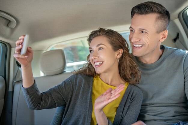 Femme avec smartphone et homme en voiture