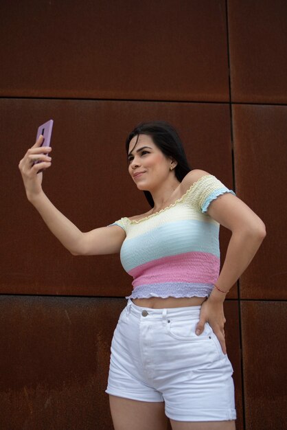 Femme avec smartphone prenant des selfies dans la rue