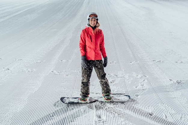 Femme avec snowboard sur la piste de ski. Equitation en soirée