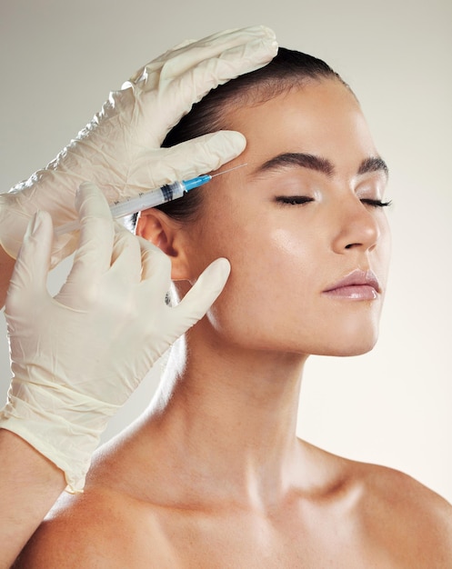 Femme de soins de la peau et aiguille pour les cosmétiques botox et procédure pour la dermatologie du bien-être et sur fond de studio Femme fille et injection pour la chirurgie plastique soins du visage et remplissage pour une peau lisse