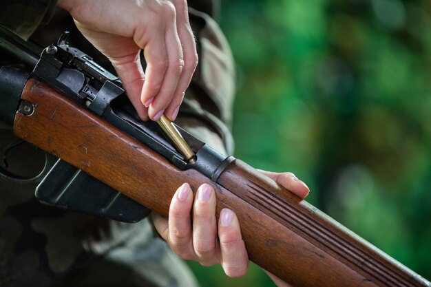 Photo une femme soldat insère une cartouche dans la chambre d'un fusil auto-rechargé vue rapprochée