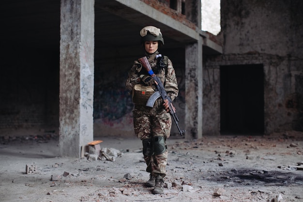 Femme soldat ukrainienne avec une arme dans ses mains dans un bâtiment détruit Guerre entre l'Ukraine et la Russie