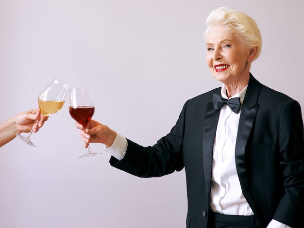 femme sommelier senior en smoking avec verre ou vin rouge à la fête