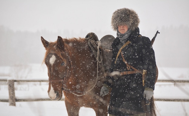 Femme avec son cheval brun en hiver