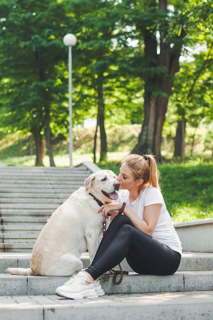 Femme avec son chien assis dans les escaliers dans le parc amitié entre l'animal et le propriétaire