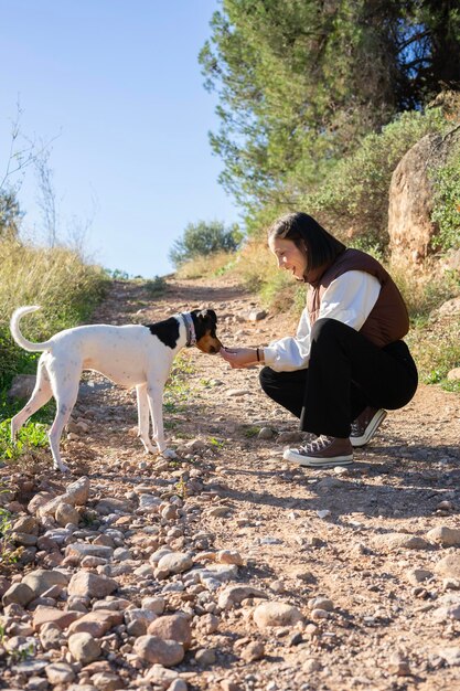 Photo une femme et son chien jouent et courent au milieu de la forêt