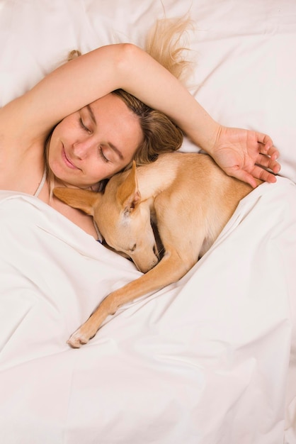 Femme avec son chien lévrier dans un lit blanc