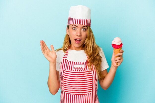 Femme de sorbetière caucasienne tenant une glace isolée sur fond bleu surpris et choqué.