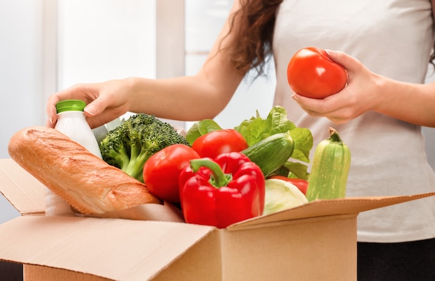 Une femme sort des aliments frais de la boîte, livraison à domicile, déballage des produits