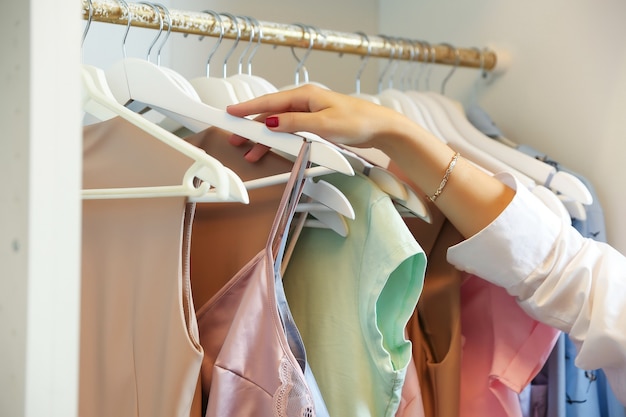 femme sort un cintre avec des vêtements du placard