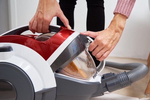 Femme sort le conteneur de poussière de l'aspirateur