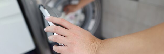 Une femme sort du linge propre de la machine à laver en gros plan