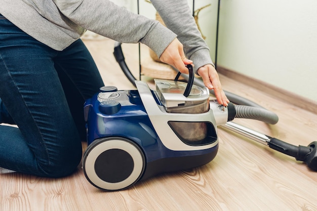 Femme sort le filtre à poussière de l'aspirateur à la maison contenant plein de saleté tâches ménagères