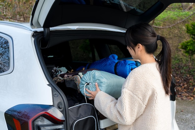 La femme sort la tente de camping de la voiture.