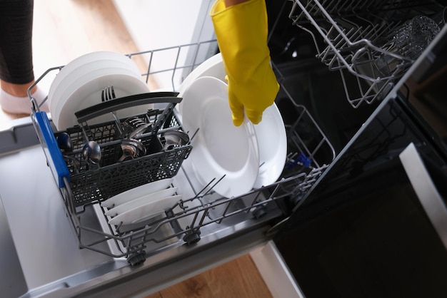 Une femme sort de la vaisselle propre du lave-vaisselle