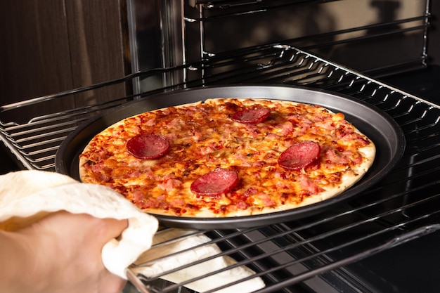 Femme sortant une pizza prête du four électrique