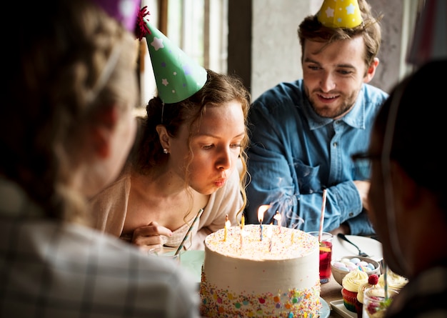 Femme soufflant des bougies sur le gâteau sur sa célébration de fête d&#39;anniversaire