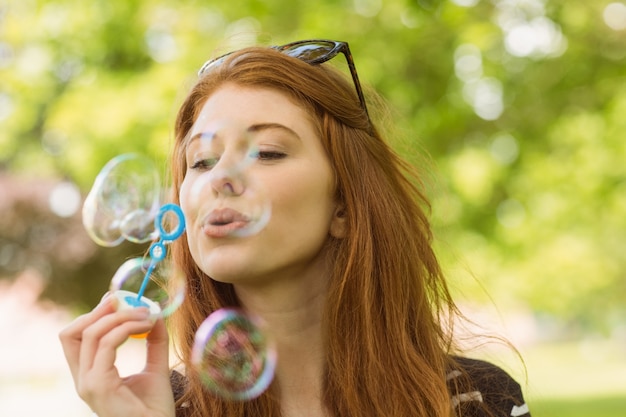 Femme soufflant des bulles au parc