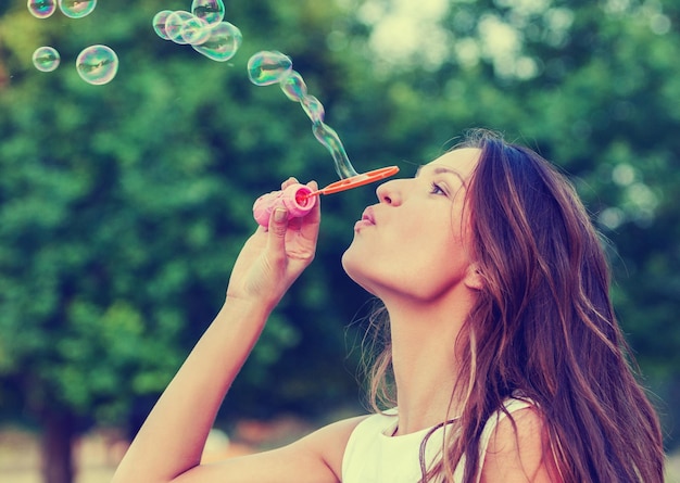 Femme soufflant des bulles de savon dans le parc