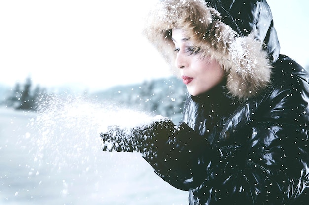 Photo une femme soufflant de la neige en hiver