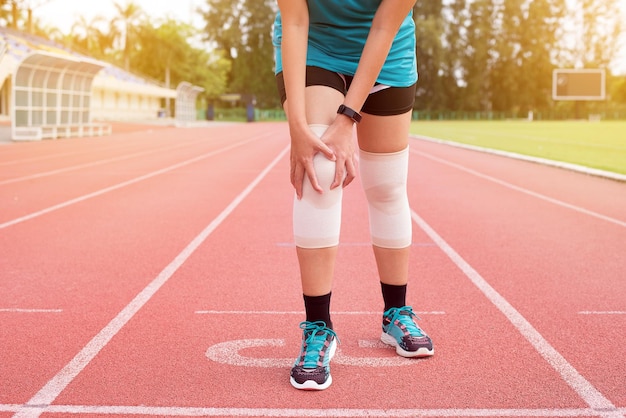 Femme souffrant de douleurs au genou pendant la course et l'entraînement à l'extérieur