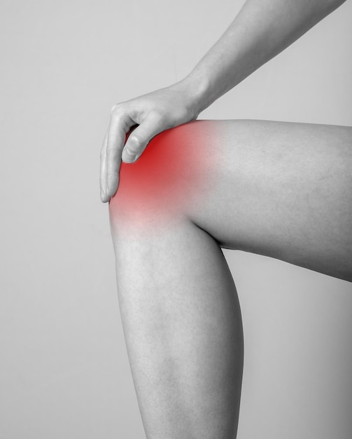 Femme souffrant de douleurs au genou tendinite entorses souches larmes arthrite pression répétée conséquences pied féminin gros plan noir et blanc