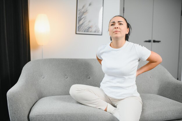 Femme souffrant de douleurs graves à la tête et au cou alors qu'elle était assise sur le canapé à la maison