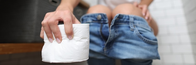 Une femme souffrant d'inconfort est assise sur les toilettes