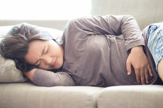 Femme Souffrant De Maux D'estomac Sur Un Canapé