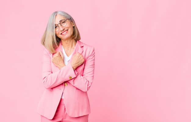 femme souriant joyeusement et célébrant, les poings serrés et les bras croisés, se sentant heureux et positif