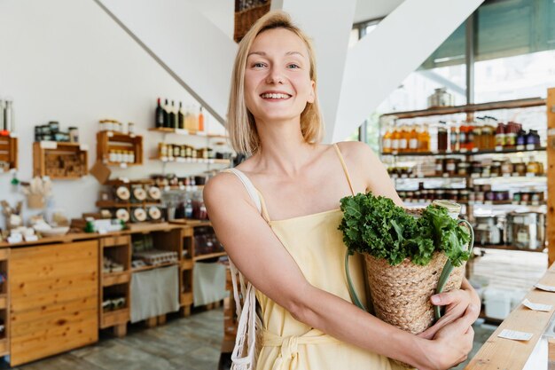 Une femme souriante achète de la nourriture biologique et des produits écologiques dans un magasin durable sans plastique