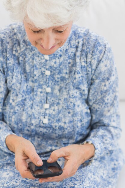 Femme souriante âgée à l&#39;aide d&#39;un smartphone