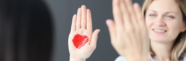 Femme souriante agitant sa main avec un coeur rouge dessiné réunions romantiques et concept de rencontres