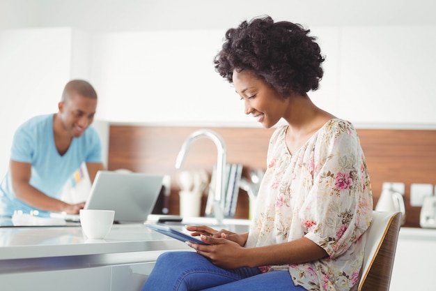 Femme souriante à l&#39;aide de tablette dans la cuisine