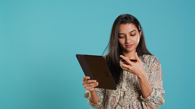 Une femme souriante ajoute un moyen de paiement sur le site d'achat à l'aide d'une tablette