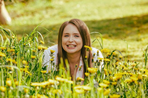 Femme souriante allongée sur le champ de pissenlit