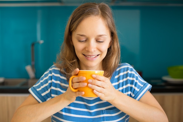 Photo femme souriante appréciant boire du thé dans la cuisine