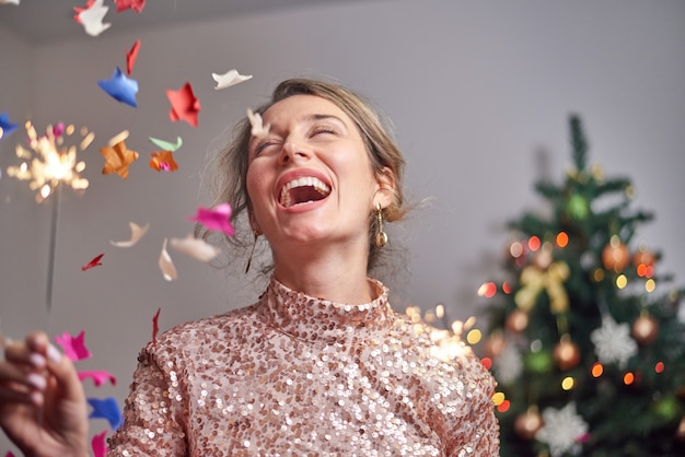 Femme souriante avec arbre de Noël et cierges magiques