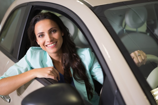 Femme souriante, assis au volant de sa nouvelle voiture