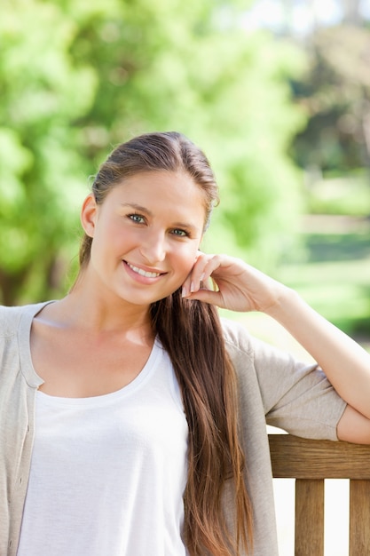 Femme souriante assise sur un banc dans le parc