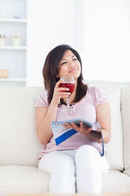 Femme souriante assise sur un canapé et tenant un verre de vin