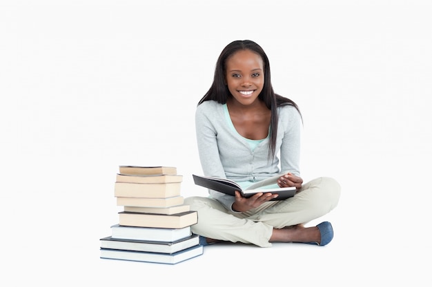 Femme souriante assise à côté d&#39;une pile de livres