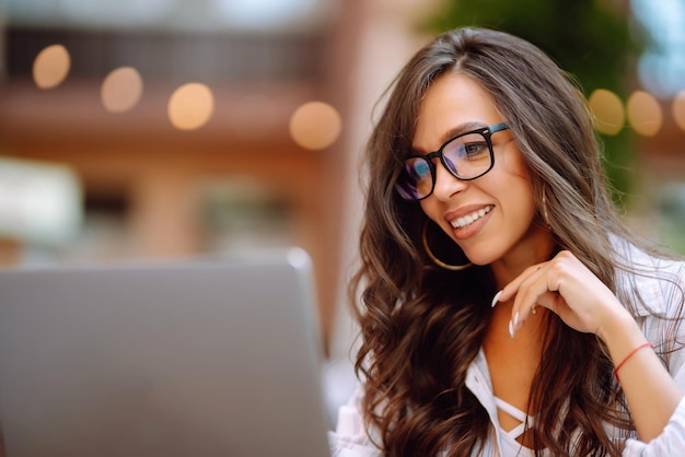 Femme souriante assise dans le café et travaillant sur un ordinateur portable Concept d'éducation en ligne indépendant