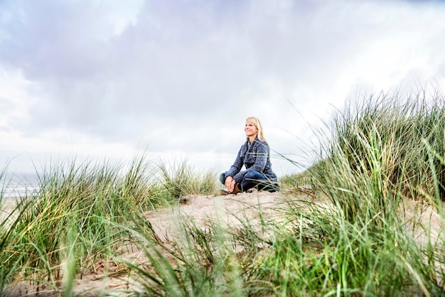 Femme souriante assise dans les dunes