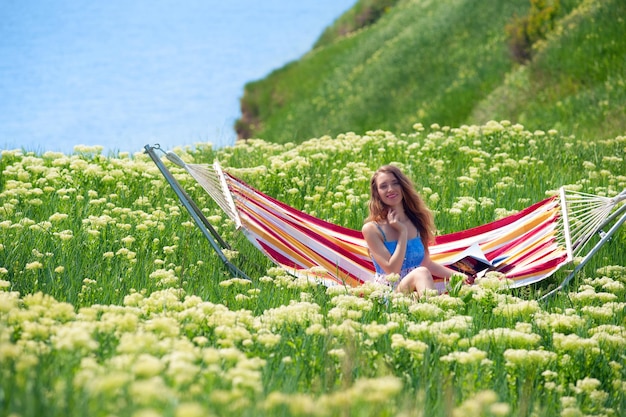 Femme souriante assise dans un hamac parmi l'achillée en fleurs